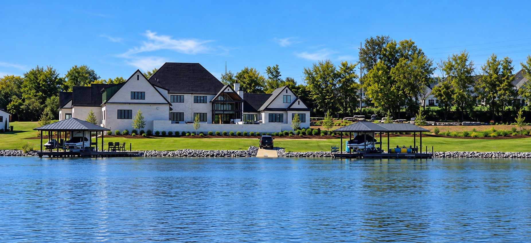 The Serenade, a lakefront residence seen from the water, with two boathouses on the shoreline