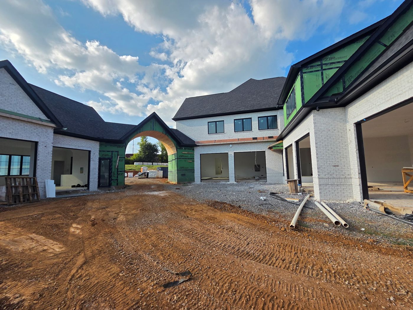 Entry courtyard with brick wings and arched porte cochere framed in sheathing
